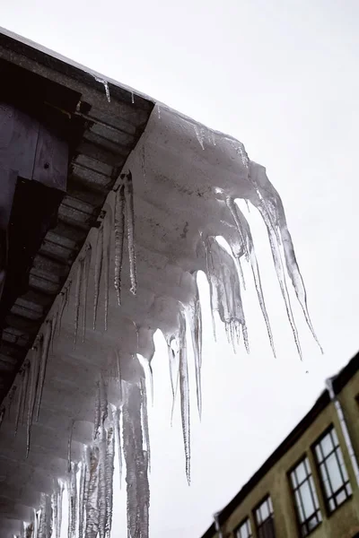 Hosszú és éles jégcsapok a tetőn. — Stock Fotó