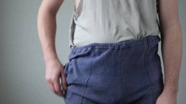 Paçavralar içinde işsiz bir adam ceplerini boşaltıyor.