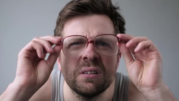 Молодий чоловік дивиться через величезні окуляри в шоці з несподіваним виразом . — стокове відео