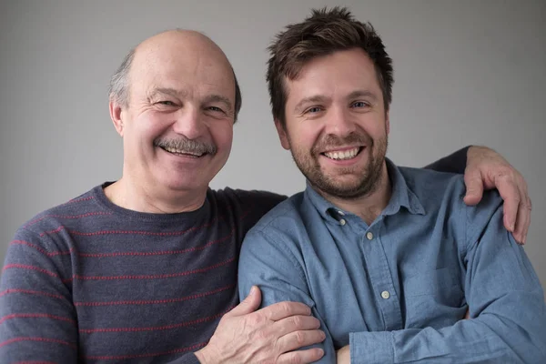 Lächelnder älterer Herr mit seinem erwachsenen Sohn mit positiver Stimmung — Stockfoto