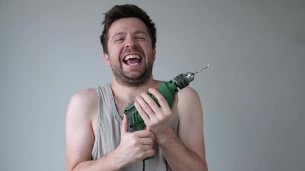Божевільний молодий чоловік божевільний робить ремонт тримає дриль в руках . — стокове відео