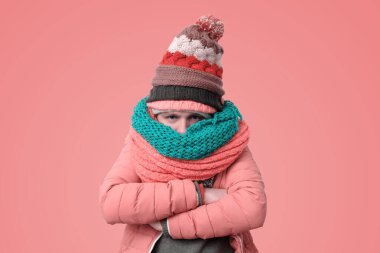 Handsome caucasian funny man in several hats and scarfs being offended or feeling cold