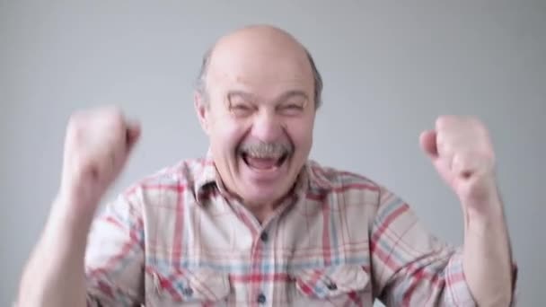 Senior hispanic celebrating his success clenching fists, feeling happy and excited — Stock Video