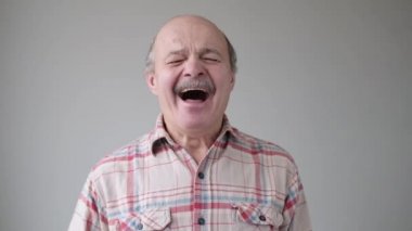 Yaşlı kel adam sıkıldı ve esniyor.