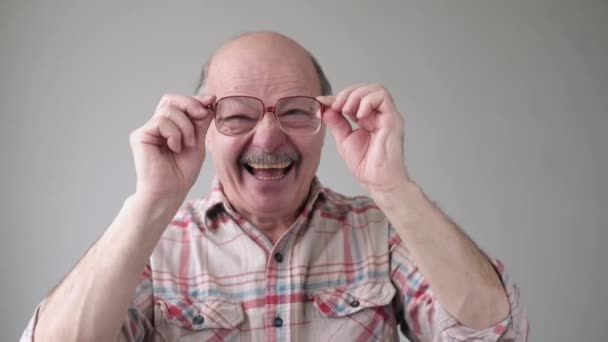 Красивий старший чоловік дивиться через окуляри посміхаючись — стокове відео