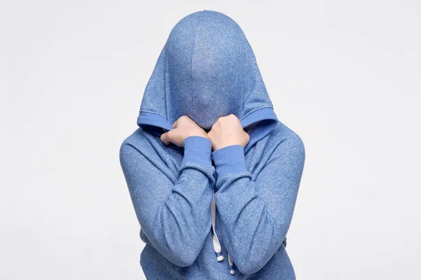 Nastolatka chowa twarz pod niebieskim swetrem przerażona i zestresowana — Zdjęcie stockowe