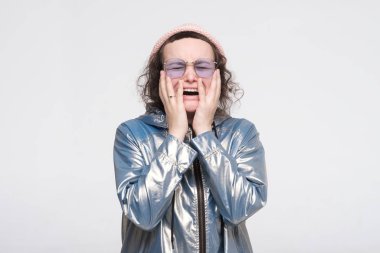 Gözlüklü ve pembe şapkalı umutsuz beyaz kadın televizyondaki son haberlerle dehşete düştü..