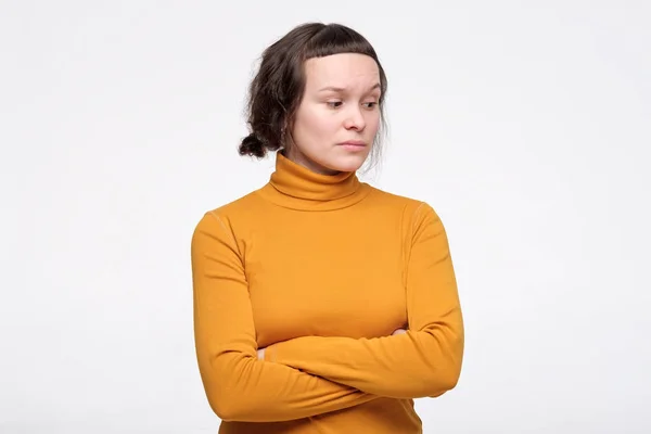 Młoda kobieta w żółtych ubraniach trzyma ręce złożone, mając nieufny podejrzliwy wygląd — Zdjęcie stockowe