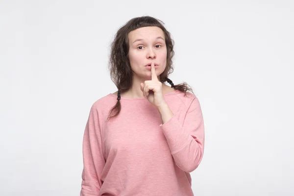 Young woman placing finger on lips asking shh, be quiet. — Stock Photo, Image