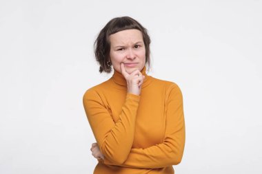 Suratı asık genç bir kadın şüpheyle ve şüpheyle bakıyor bir şeyden şüpheleniyor.