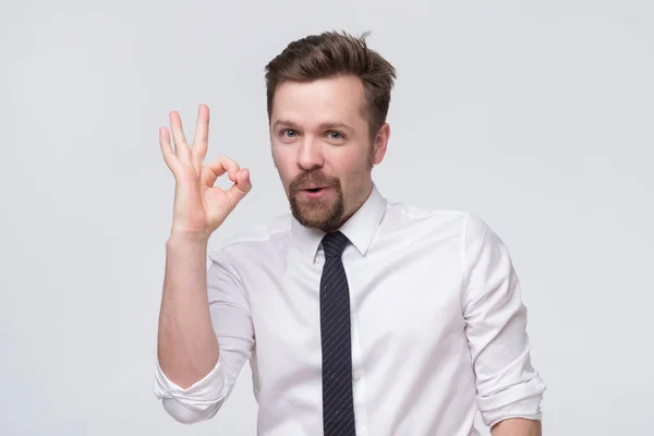 Feliz joven con camisa y corbata haciendo gestos aprobando el signo y sonriendo . — Foto de Stock