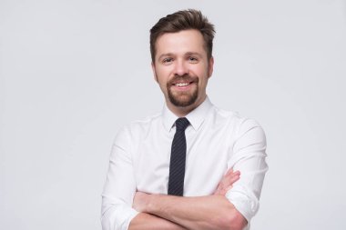 Beyaz tişörtlü ve siyah kravatlı yakışıklı Avrupalı iş adamı kameranın önünde duruyor.