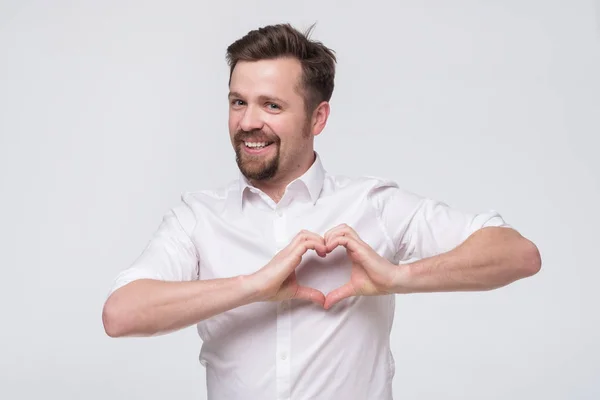 Vriendelijke man met een glimlachende baard en hartvormig handgebaar — Stockfoto