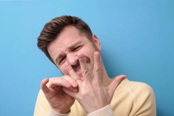 Mann versucht Hochzeitsband aus seinem Finger zu schieben. über die Ehe nachdenken oder darüber nachdenken. — Stockbild Mann versucht Hochzeitsband vom Finger zu schieben. — Stockfoto