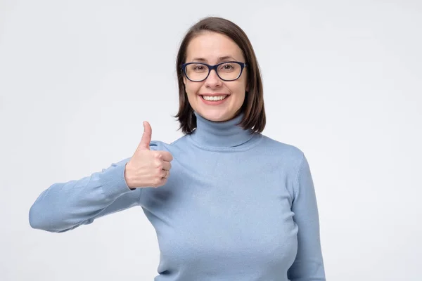 Mujer casual joven en gafas en ropa azul aislada sobre fondo blanco mostrando los pulgares hacia arriba — Foto de Stock