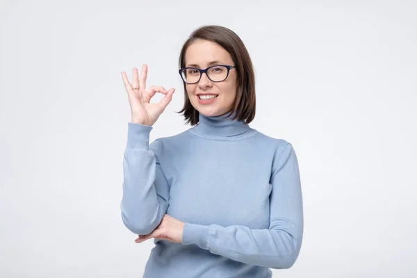Взрослая белая женщина с широкой улыбкой в очках, показывающих ОК символ с пальцами . — стоковое фото
