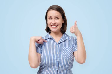 Kadın model başparmağını kaldırıyor, jest yapıyor, kendini tatmin ediyor.