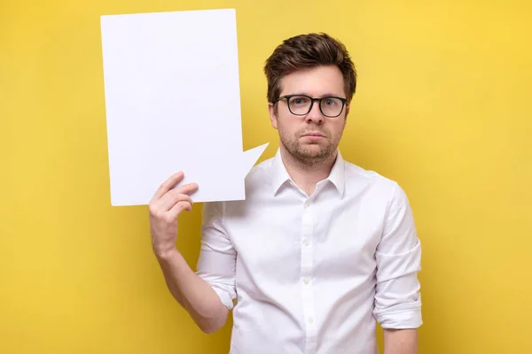 Man in glasses showing blank white billboard sign isolated on yellow wall. — Stock Photo, Image