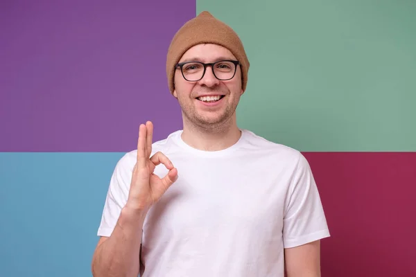 Man showing OK gesture with hands against colored background — 스톡 사진