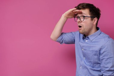 Gözlüklü adam uzaklardan, kopyasına ve pembe duvarına bakıyor..