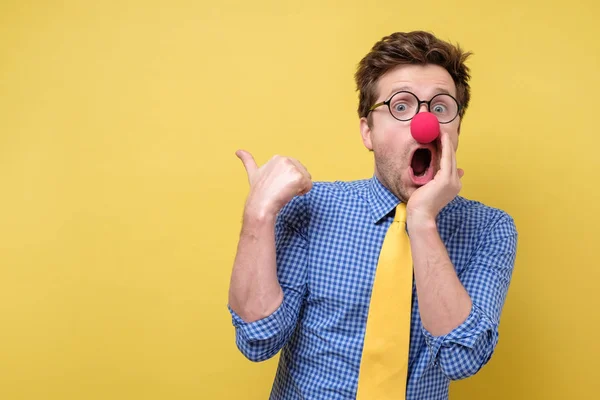 Shocked man with red clown nose looking camera showing pointing on copyspace. Clown, corcus or show concept. — Stock Photo, Image