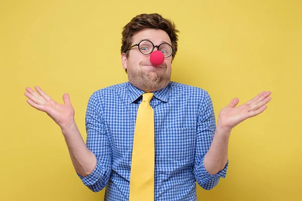 Giovane buffo clown uomo con naso rosso e cravatta gialla mostrando ignoranza — Foto Stock
