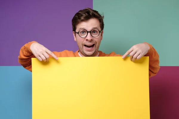 Guapo chico en gafas mostrando vacío copyspace amarillo — Foto de Stock