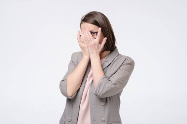 Güzel, neşeli bayan iş arkadaşı ellerini kullanarak yüzünü kapatıyor.