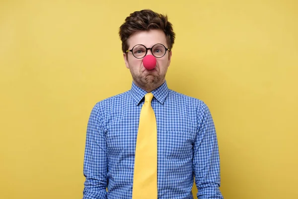 Caucasico giovane uomo in rosso clown naso essere irritato e triste . — Foto Stock