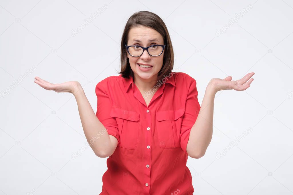 wondered woman in glasses and red shirt isolated on white wall. I do not know what to choose