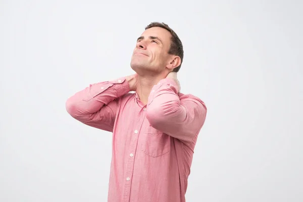 Взрослый мужчина в розовой рубашке с болью в шее из-за остеохондроза, грыжи или спазма — стоковое фото