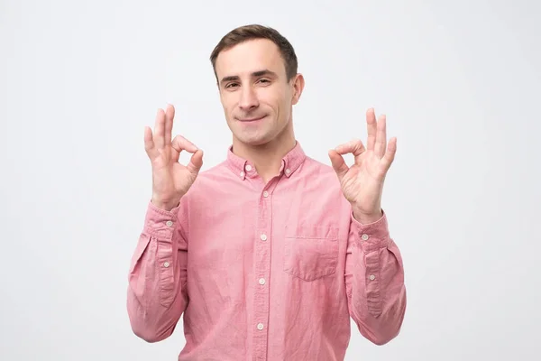 Cheerful italian young man in pink shirt showing okay gesture — 스톡 사진