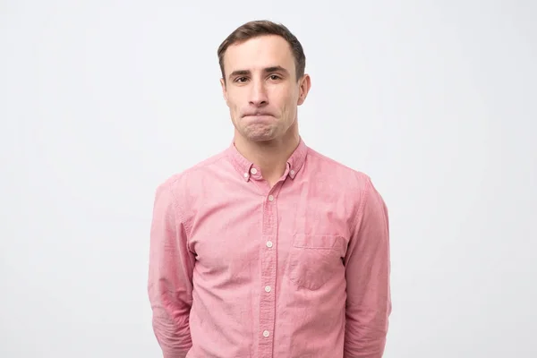 Jongeman in roze shirt kijkt naar beneden en is van streek van het nieuws — Stockfoto