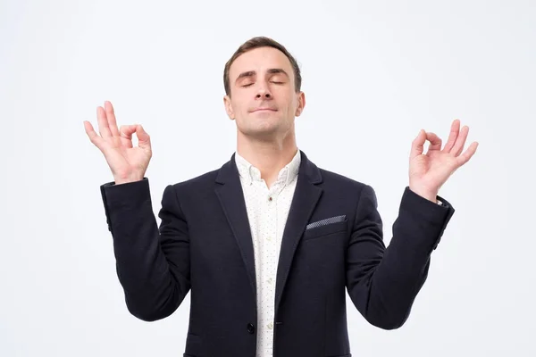 Hombre de traje y camisa blanca de pie, brazos levantados, ojos cerrados con gesto de yoga y meditación — Foto de Stock