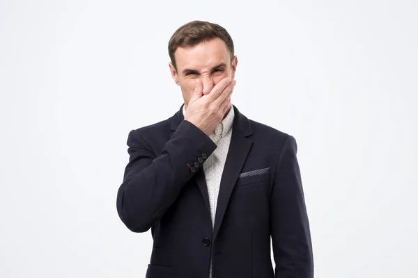 Young man in suit closing nose due to bad smell — 스톡 사진