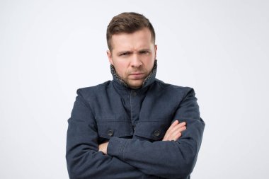 Elleri katlı, kalın ceketli genç yakışıklı adam.