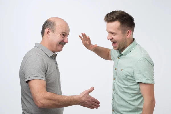 Dois homens brancos maduros pai e filho apertando as mãos fazendo um acordo . — Fotografia de Stock