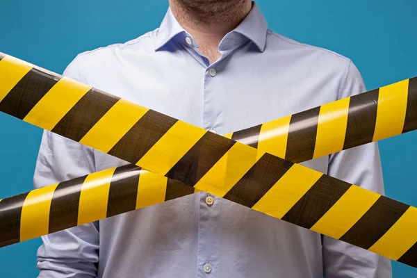 De mens staat achter zwarte en gele lijnen van barrière tape die doorgang verbiedt. — Stockfoto
