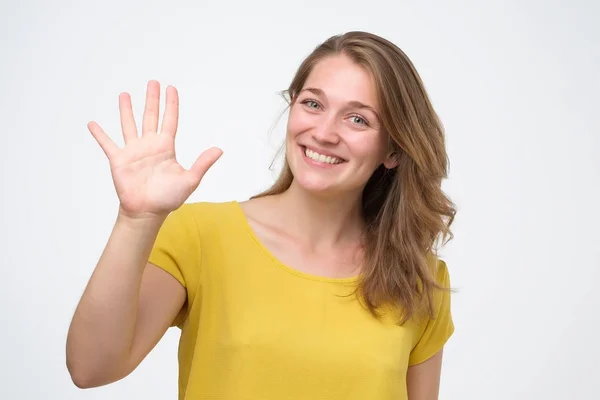 Приваблива дружня молода жінка, що посміхається щасливо, показує п'ять пальців . — стокове фото