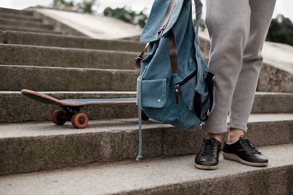 Teenager girl with backpack sitanding on the steps near her skate — Stock Photo, Image