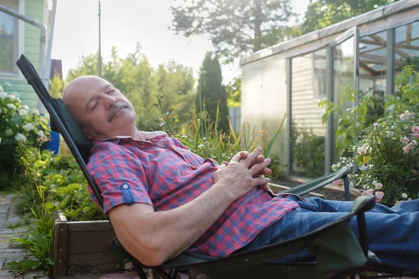 Взрослый мужчина в повседневной одежде сидит в шезлонге и отдыхает, вздремнув . — стоковое фото