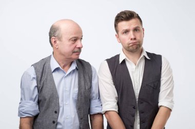 İki beyaz adam, baba ve oğul somurtuyor ve kaşlarını çatıyor. Acımasız sözlerden rahatsız oluyorlar..