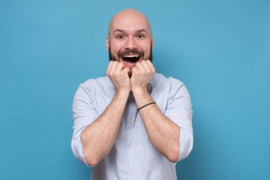 Lucky caucasian bearded man is excited with news or offer in tv shop.