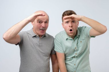 Two men looking forward with big expectations being shocked.