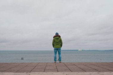 Woman standing alone on pier looking at sea at cold winter day in Tallinn Estonia