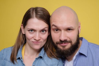 Young caucasian couple looking with doubt at camera having sceptical faces.