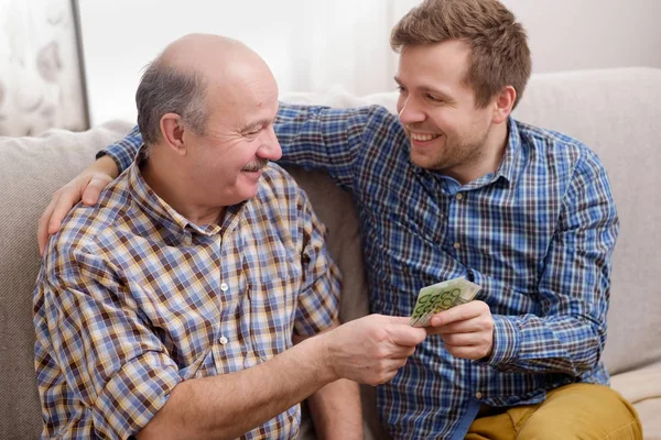 Пожилой отец одалживает деньги своему взрослому сыну — стоковое фото