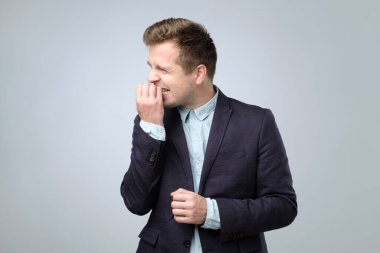 Takım elbiseli, tırnaklarını yiyen, gergin, beyaz bir genç. Kötü alışkanlık kavramı.