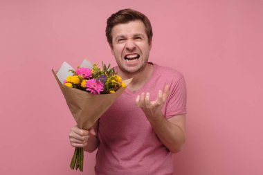 Kızgın aşık ya da pembe elbiseli kalbi kırık bir adam elinde çiçek buketiyle dikiliyor..