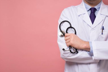 Pembe duvarda steteskop ve beyaz elbiseli bir doktor ya da stajyer.